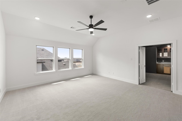 carpeted empty room featuring vaulted ceiling and ceiling fan