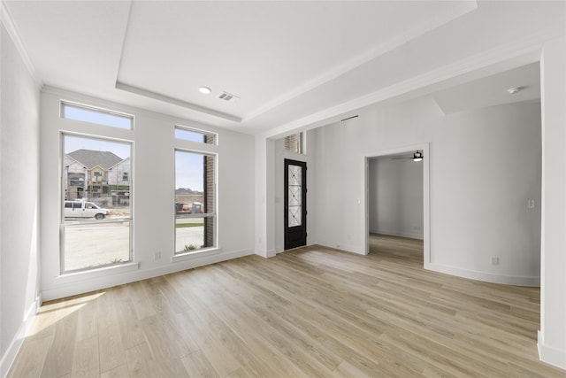 unfurnished room with light wood-type flooring and a tray ceiling