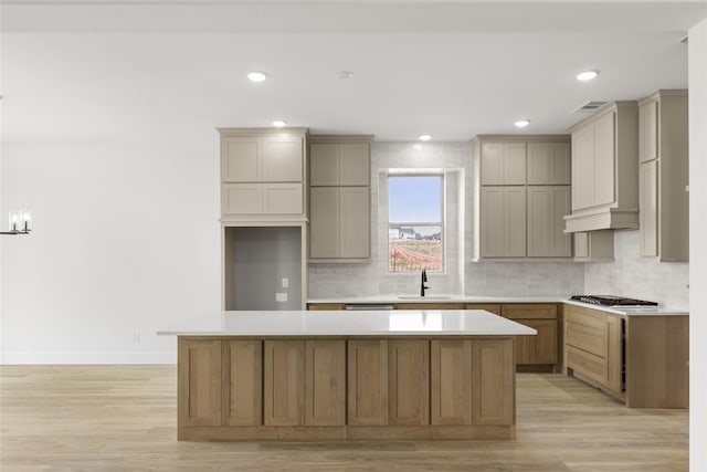 kitchen with a kitchen island, sink, tasteful backsplash, and light hardwood / wood-style flooring