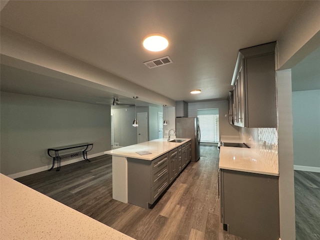 kitchen featuring visible vents, dark wood finished floors, gray cabinetry, light countertops, and a sink