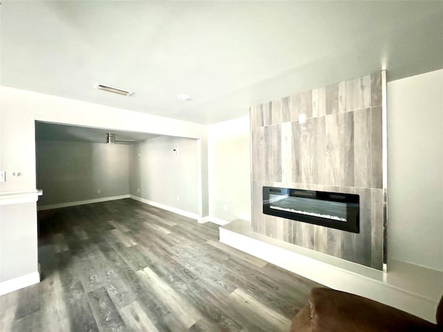 unfurnished living room featuring baseboards, visible vents, wood finished floors, and a fireplace