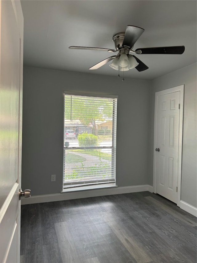 spare room with ceiling fan, dark wood-style floors, and baseboards