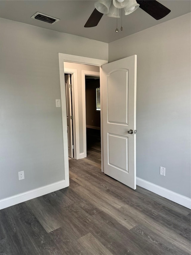 unfurnished room with visible vents, a ceiling fan, baseboards, and dark wood-style floors