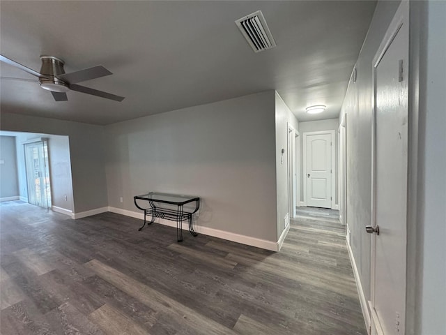 interior space with baseboards, ceiling fan, dark wood-style flooring, and visible vents
