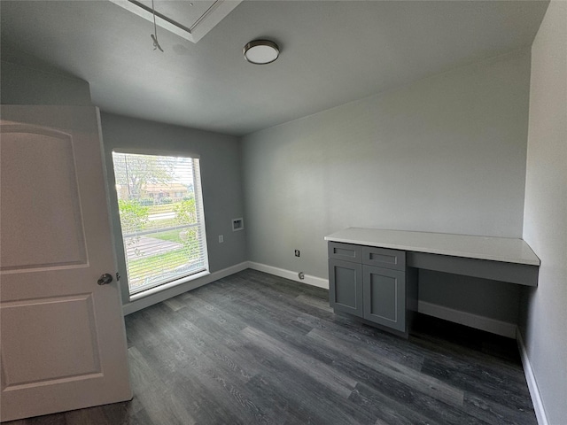 unfurnished office with baseboards, attic access, and dark wood finished floors
