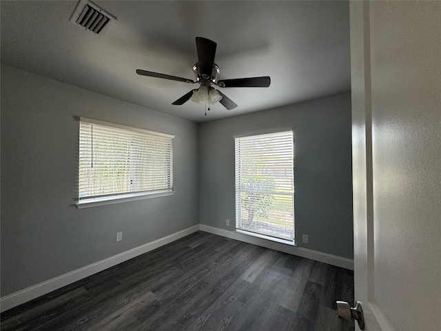 spare room featuring baseboards, ceiling fan, visible vents, and dark wood finished floors