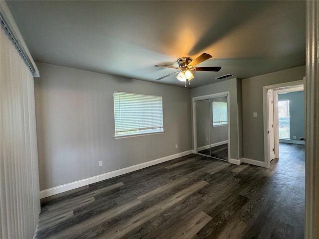 unfurnished bedroom with a ceiling fan, dark wood-style flooring, visible vents, baseboards, and a closet