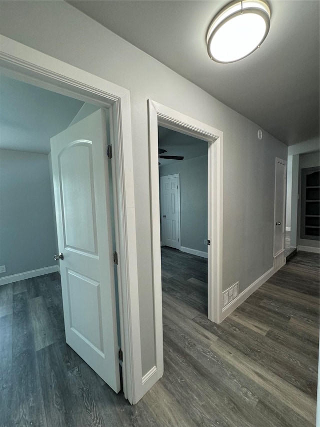 hallway with dark wood-style flooring and baseboards