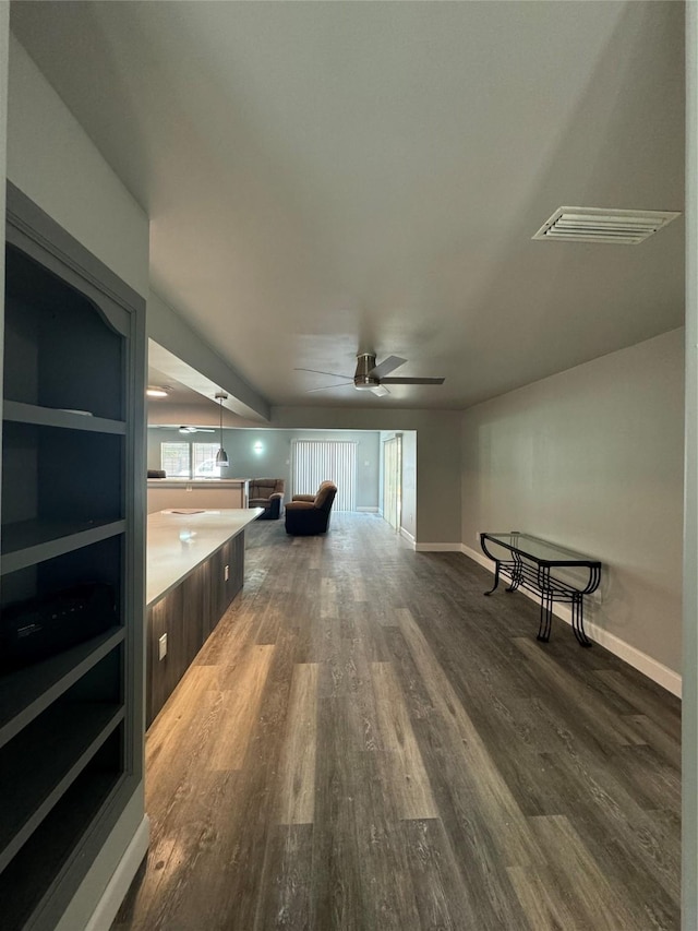 unfurnished living room with baseboards, ceiling fan, dark wood-style floors, and visible vents