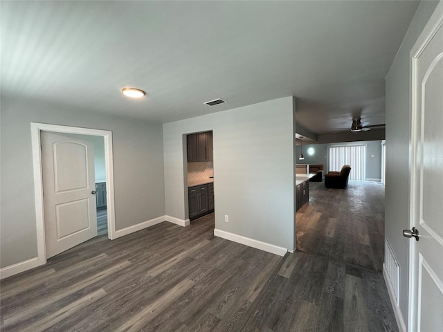 spare room with baseboards, ceiling fan, dark wood-style floors, and visible vents