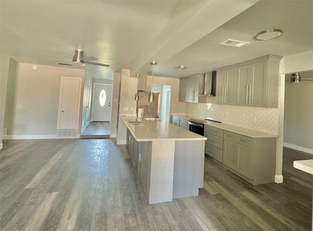 kitchen featuring wood finished floors, baseboards, light countertops, gray cabinets, and wall chimney exhaust hood