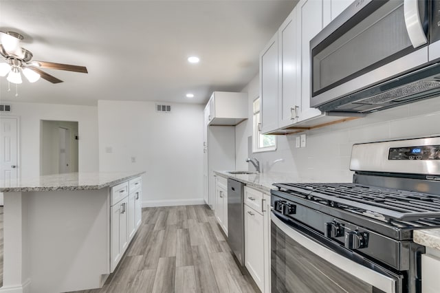 kitchen featuring stainless steel appliances, light hardwood / wood-style floors, and white cabinetry