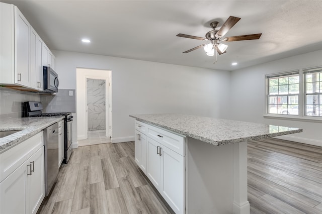 kitchen with ceiling fan, light wood-type flooring, a center island, and white cabinetry