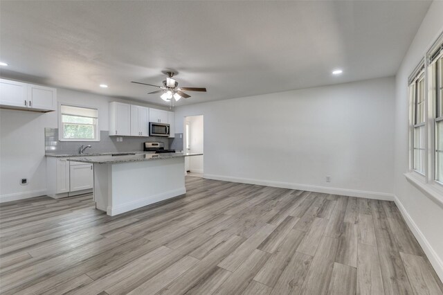 kitchen featuring light wood-type flooring, white cabinetry, light stone countertops, and ceiling fan