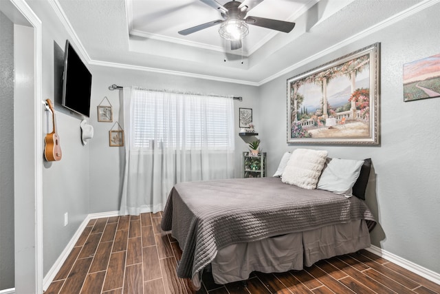 bedroom featuring ceiling fan, dark wood-type flooring, crown molding, and a tray ceiling