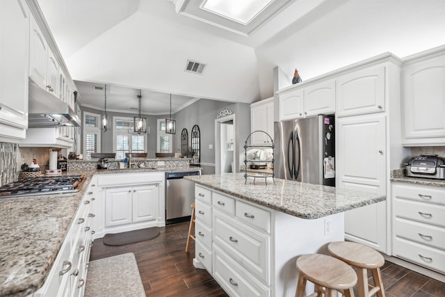 kitchen with stainless steel appliances, hanging light fixtures, a center island, a kitchen bar, and dark hardwood / wood-style floors