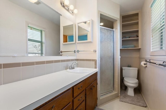 bathroom with toilet, a wainscoted wall, vanity, and a stall shower