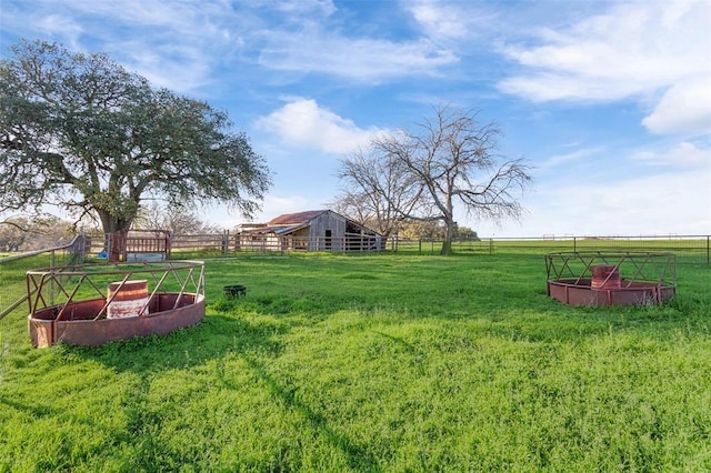 view of yard with a rural view, an outdoor structure, and fence