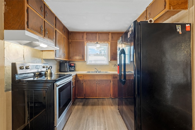 kitchen with range with electric stovetop, light hardwood / wood-style floors, sink, and black refrigerator