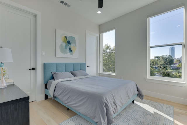 bedroom with light hardwood / wood-style floors, multiple windows, and ceiling fan