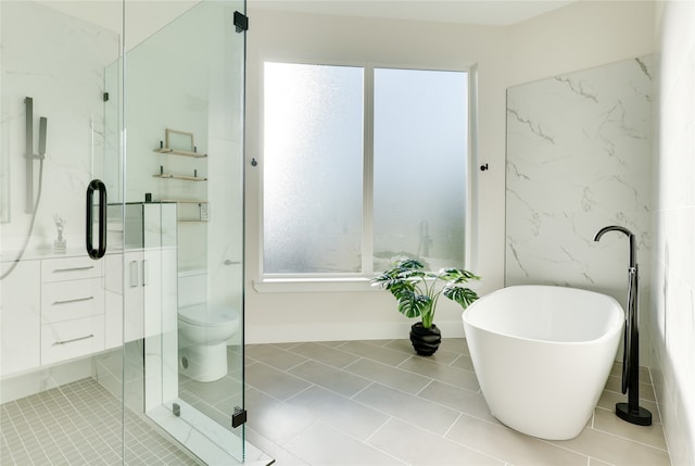 bathroom with a healthy amount of sunlight, toilet, plus walk in shower, and tile patterned floors