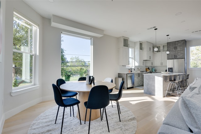 dining area with light wood-type flooring, a healthy amount of sunlight, and sink