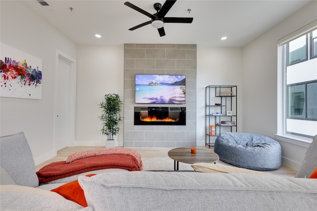 living room with hardwood / wood-style floors, a tiled fireplace, and ceiling fan