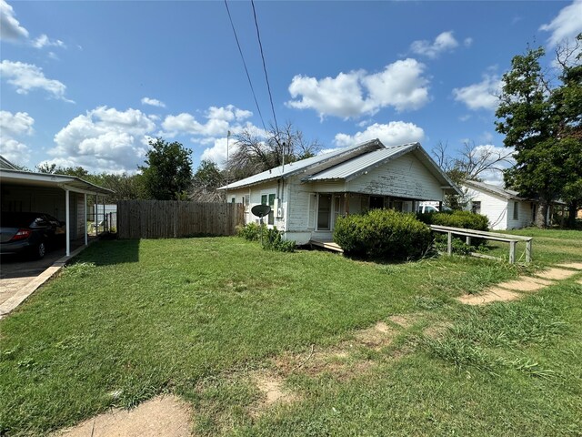 view of side of property featuring a lawn and a carport