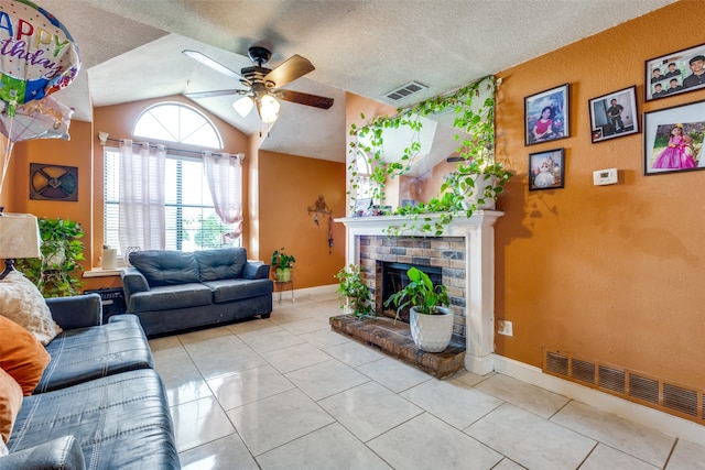 living room with a textured ceiling, vaulted ceiling, light tile patterned floors, and ceiling fan