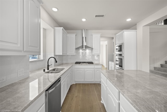 kitchen featuring appliances with stainless steel finishes, dark hardwood / wood-style floors, white cabinetry, and wall chimney range hood