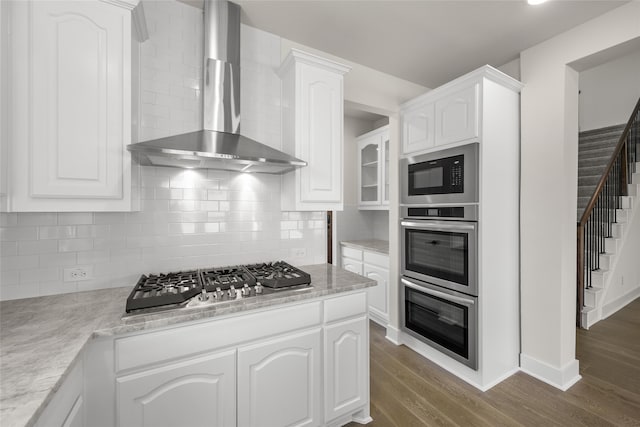 kitchen featuring dark hardwood / wood-style floors, white cabinetry, stainless steel appliances, and wall chimney range hood