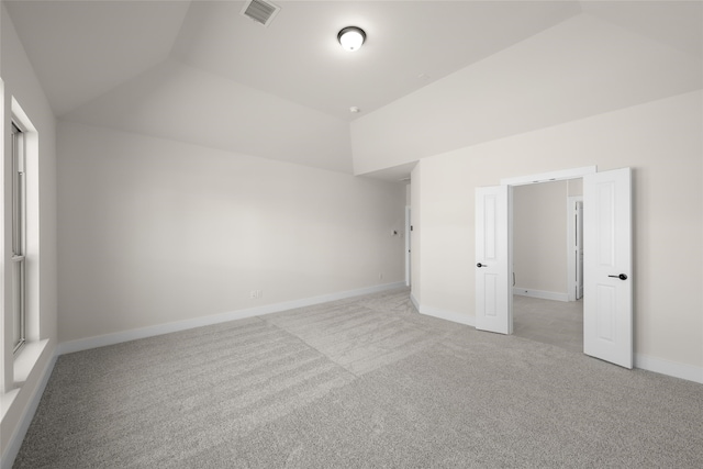 unfurnished room with lofted ceiling and light carpet