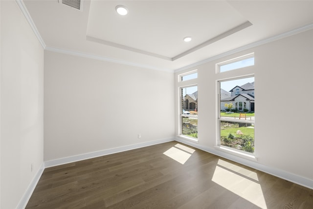 unfurnished room with a raised ceiling, crown molding, and dark wood-type flooring