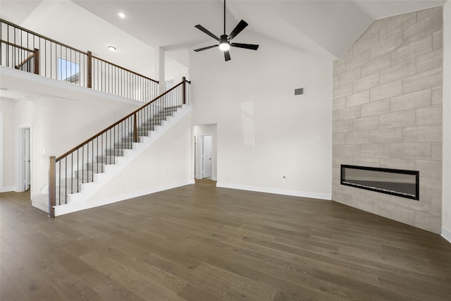 unfurnished living room with a tiled fireplace, ceiling fan, high vaulted ceiling, and dark hardwood / wood-style floors