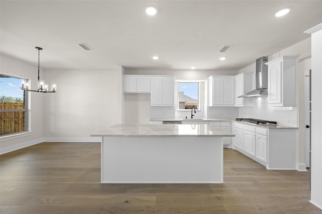 kitchen with white cabinets, plenty of natural light, and wall chimney exhaust hood