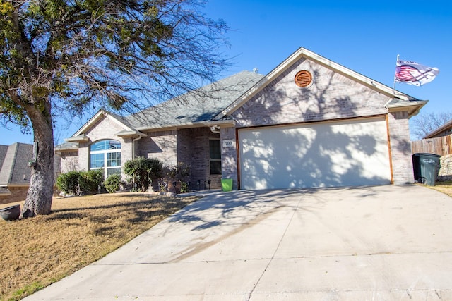 ranch-style home featuring a garage, driveway, fence, and brick siding