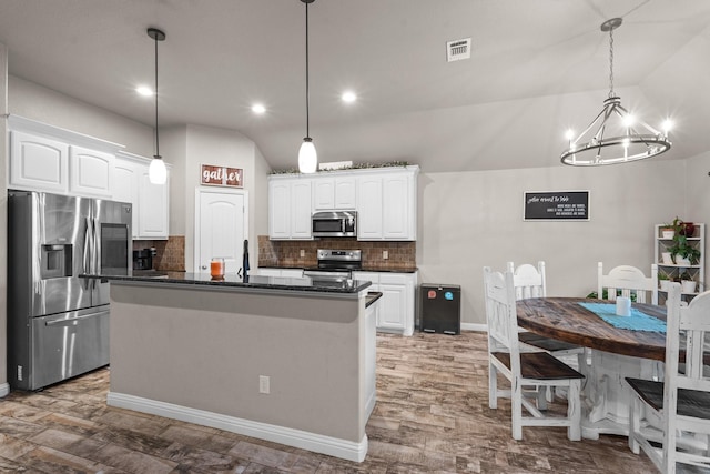 kitchen featuring lofted ceiling, stainless steel appliances, visible vents, and white cabinets