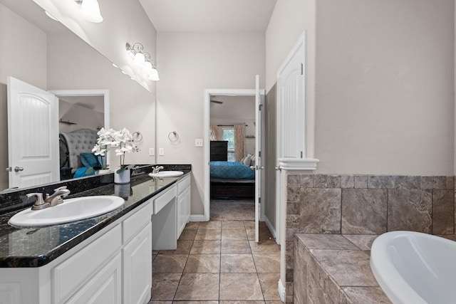 bathroom with double vanity, ensuite bath, a washtub, and a sink