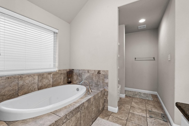 bathroom with lofted ceiling, visible vents, a garden tub, and baseboards