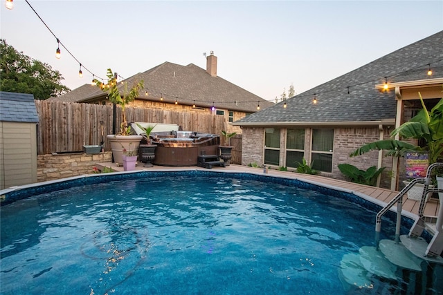 view of swimming pool featuring an outdoor structure, a fenced backyard, a fenced in pool, and a hot tub