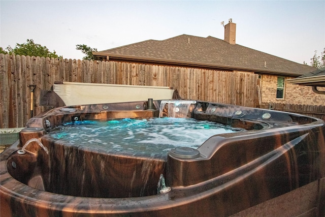 view of pool with a hot tub and fence