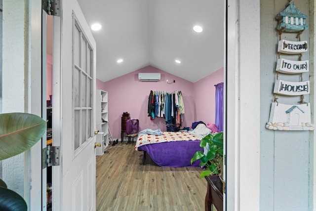 bedroom featuring vaulted ceiling, an AC wall unit, wood finished floors, and recessed lighting