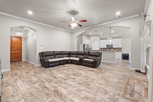 living area with arched walkways, ornamental molding, visible vents, and light wood-style floors