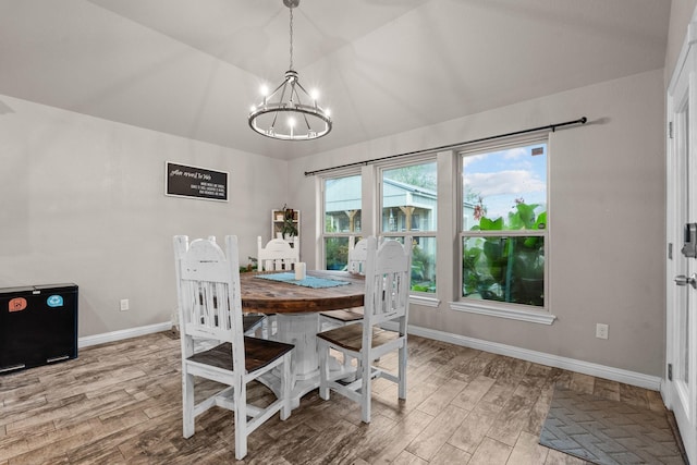 dining space with lofted ceiling, baseboards, a notable chandelier, and wood finished floors