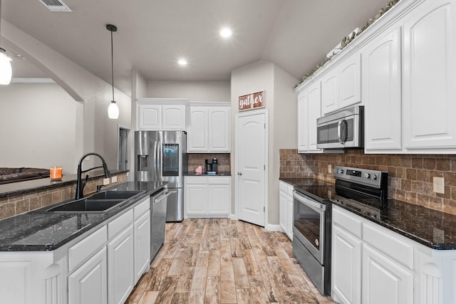 kitchen with stainless steel appliances, a sink, white cabinets, and light wood-style floors