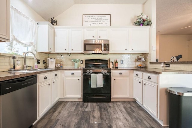 kitchen featuring appliances with stainless steel finishes, vaulted ceiling, a sink, white cabinets, and decorative backsplash