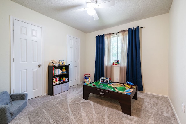 rec room featuring light carpet, ceiling fan, and a textured ceiling