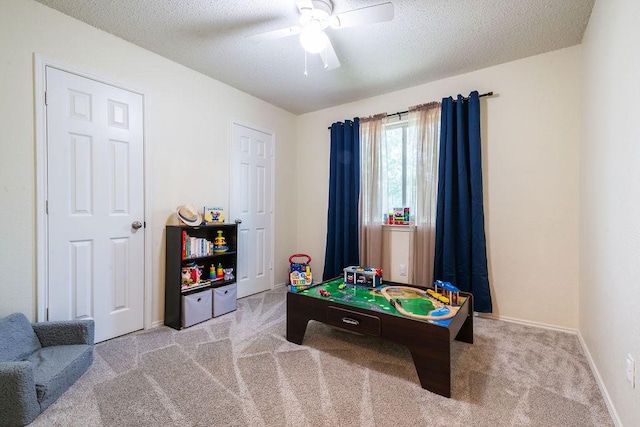 recreation room featuring carpet floors, ceiling fan, a textured ceiling, and baseboards