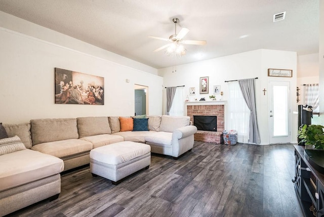living area with dark wood-style flooring, a ceiling fan, and a brick fireplace