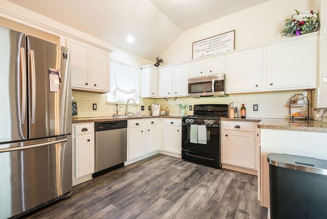 kitchen with lofted ceiling, dark hardwood / wood-style floors, decorative backsplash, appliances with stainless steel finishes, and white cabinetry